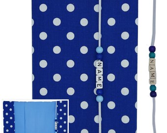 May include: Blue book cover with white polka dots and a blue and white beaded bookmark with the word "NAME" spelled out. The book cover is closed and the bookmark is hanging from the top of the cover.