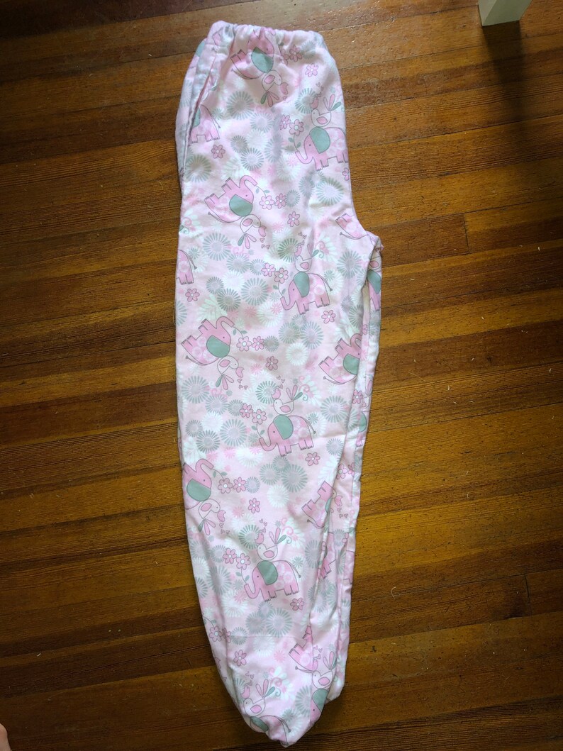 May include: Pink pyjama bottoms with a white background and a pattern of grey elephants and pink flowers.