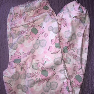 May include: Pink and grey patterned leggings with a design of elephants and birds. The leggings have an elasticated waistband.