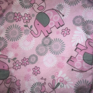 May include: Pink fabric with a repeating pattern of grey and white flowers, pink elephants, and pink birds. The birds have grey wings and beaks.
