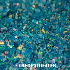 May include: Close-up of a pile of small, irregularly shaped, teal-colored stones. The stones have iridescent flashes of yellow, orange, and green. The text "THEOPALDEALER" is at the bottom of the image.