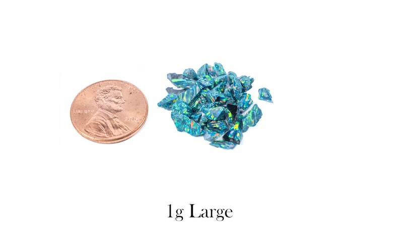 Puede incluir: Un mont&oacute;n de virutas de &oacute;palo azul-verdoso iridiscente junto a una moneda. Las piezas de &oacute;palo tienen un aspecto fracturado y reflejan m&uacute;ltiples colores. El texto "1g Large" est&aacute; en la parte inferior de la imagen.