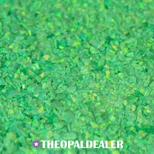 May include: Close-up of a pile of crushed green opal gemstones. The stones have a fractured appearance with varying shades of green and yellow. The text "THEOPALDEALER" is at the bottom.