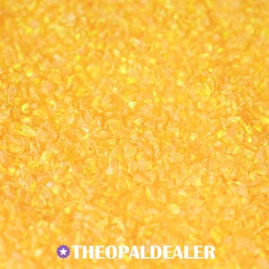 May include: Close-up of a pile of small, irregularly shaped, translucent, yellow-orange pieces. The pieces are scattered and appear to be reflective. The text "THEOPALDEALER" is at the bottom of the image.