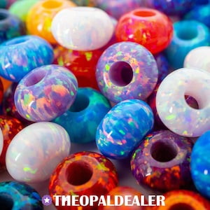 May include: A selection of vibrant opal beads in diverse forms, including round and ring-shaped. The beads showcase a spectrum of hues, including blue, purple, red, orange, and white. The text "THEOPALDEALER" is visible at the bottom.