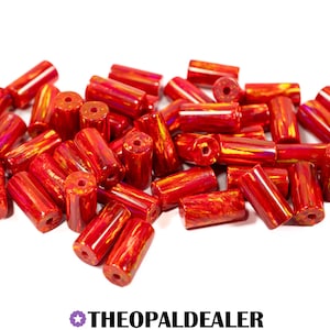 May include: A pile of red and yellow glass beads with a cylindrical shape. The beads have a glossy, iridescent finish and are drilled with a hole through the center. The text "THEOPALDEALER" is at the bottom.