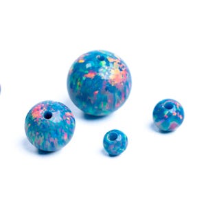 May include: Several round, blue opal beads of varying sizes are displayed against a white background. The beads have a speckled pattern with hints of pink, orange, and green. Each bead has a hole running through the center.