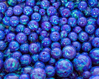 May include: A collection of blue and purple opal beads. The beads vary in size and have a glossy finish with swirls of color. Each bead has a hole for stringing. Ideal for jewelry making.