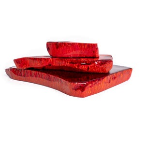 Könnte beinhalten: Vier gestapelte, unregelmäßig geformte, rote Holzblöcke. Die Blöcke haben eine glänzende Oberfläche und eine strukturierte Oberfläche mit sichtbarer Holzmaserung. Die Anordnung deutet auf eine dekorative oder künstlerische Darstellung hin, möglicherweise für die Inneneinrichtung oder ein Bastelprojekt.