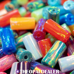 Puede incluir: Primer plano de un montón de cuentas cilíndricas de colores. Las cuentas son de varios colores, incluyendo rojo, naranja, azul, verde y blanco. Algunas cuentas tienen un brillo iridiscente. El texto "THEOPALDEALER" está en la parte inferior.