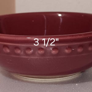 Puede incluir: Un bol de cerámica burdeos con un borde de cuentas. El bol mide 8,9 cm de diámetro y 3,2 cm de alto.