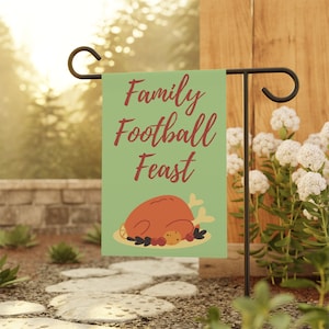 May include: A green garden flag with the text "Family Football Feast" in red lettering. A cartoon illustration of a roasted turkey on a platter with cranberries and biscuits is below the text.