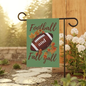 May include: A green garden flag with a brown football and fall leaves. The text on the flag reads "Football and Fall Y'all".