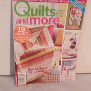 Puede incluir: Portada de la revista "Quilts and More" con un proyecto de edredón colorido. La portada incluye texto como "19 Proyectos" y "Sensational Strip Quilt". También se presentan otros proyectos de artesanía.