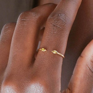 Op de afbeelding: Een gouden ring met twee kleine, ronde, gouden accenten op de band.