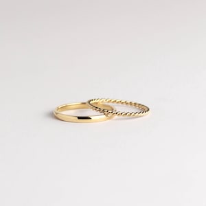 May include: Two gold rings, one with a simple band and the other with a twisted rope design.