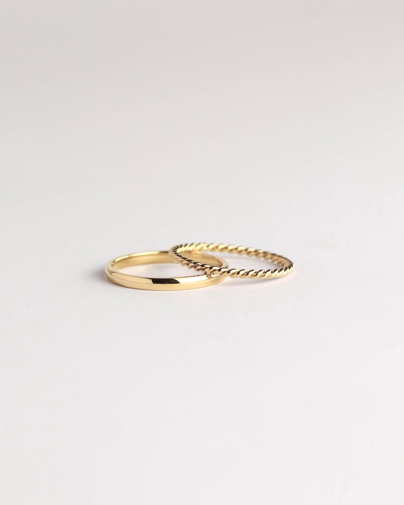 May include: Two gold rings, one with a simple band and the other with a twisted rope design.