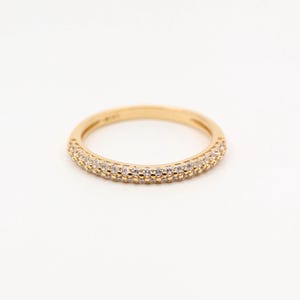 Może przedstawiać: Złoty pierścionek z podwójną rzędów małych, przezroczystych cyrkonii.