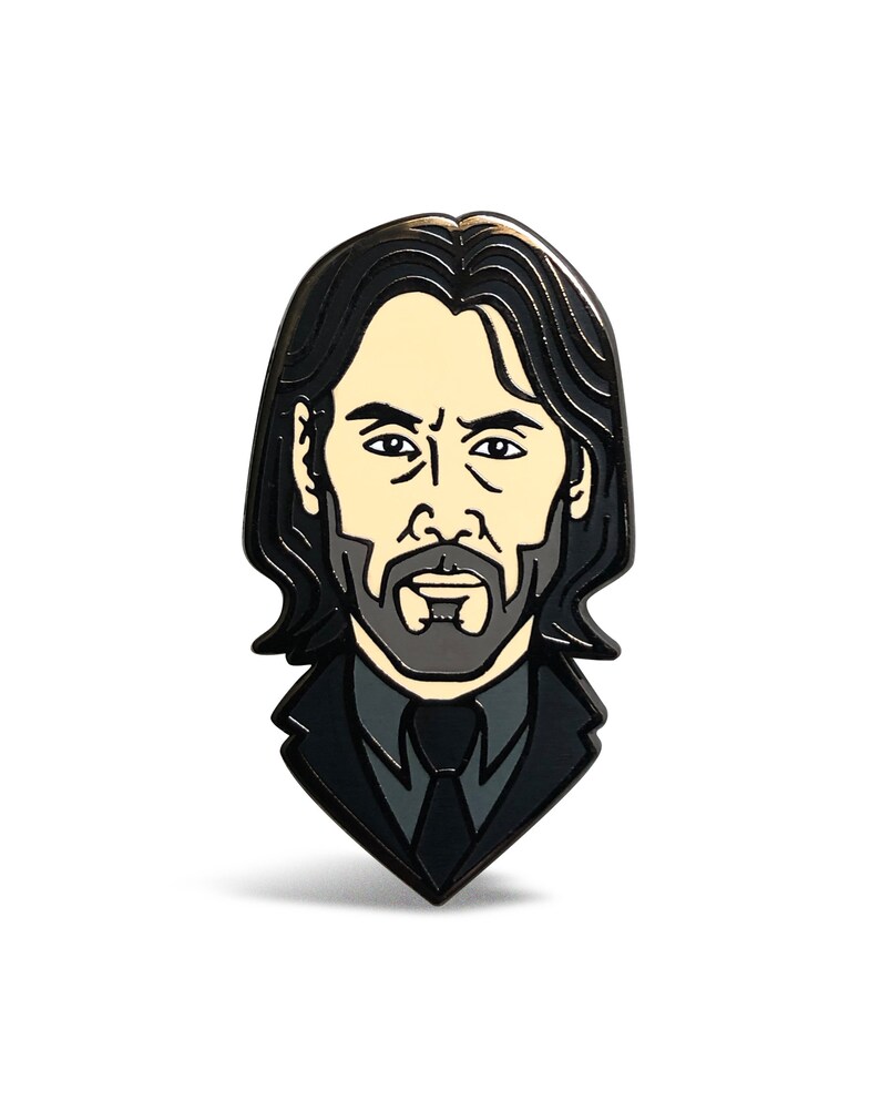 May include: Black and white enamel pin featuring a cartoon portrait of a man with long black hair, a beard, and a black suit and tie.