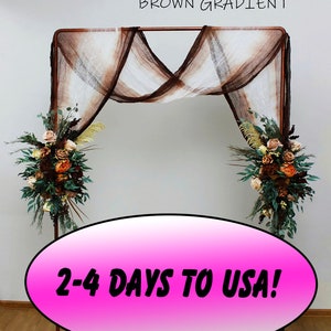 May include: A copper metal archway decorated with a brown gradient sheer fabric backdrop. The archway is adorned with two floral arrangements featuring dried flowers and greenery. The text "2-4 DAYS TO USA!" is displayed on a pink oval.