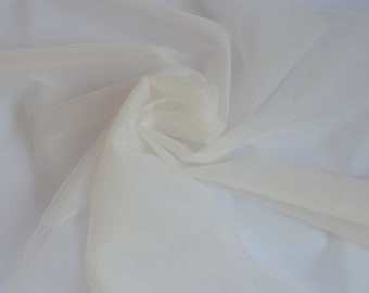 May include: A close-up shot of a white, semi-transparent fabric with a soft, flowing texture. The fabric is gathered and swirled, creating a sense of depth and movement. The material appears to be lightweight, possibly chiffon or organza.