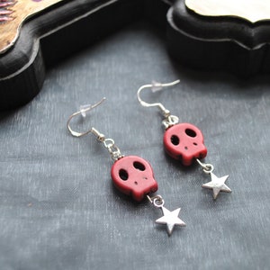 Puede incluir: Pendientes colgantes con cuentas de calavera rojas y abalorios de estrella plateada. Los pendientes tienen ganchos plateados. Un accesorio g&oacute;tico o con tem&aacute;tica de Halloween.
