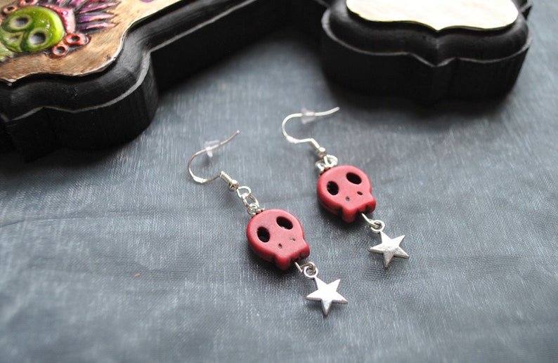 Puede incluir: Pendientes colgantes con cuentas de calavera rojas y abalorios de estrella plateada. Los pendientes tienen ganchos plateados. Un accesorio g&oacute;tico o con tem&aacute;tica de Halloween.