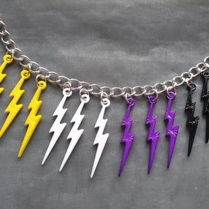 May include: A silver chain necklace with multiple lightning bolt charms. The charms are yellow, white, purple, and black.