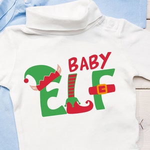 May include: White baby bodysuit with the words "BABY ELF" in red and green. The "ELF" is designed with an elf hat, striped leg, and a buckle. Light blue baby booties are next to the bodysuit. The bodysuit has a white turtleneck.
