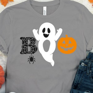 May include: Grey t-shirt featuring a white ghost, a black spider web, and an orange pumpkin with a black face. The text "BOO" is spelled out with the ghost, spider web, and pumpkin.