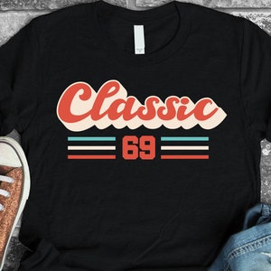 May include: Black t-shirt with a red, white, and blue retro-style graphic that says "Classic 69".