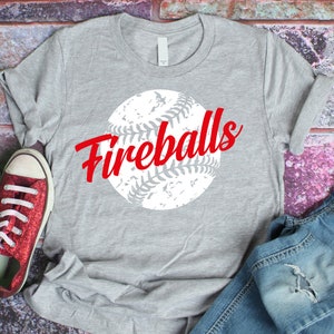 K&ouml;nnte beinhalten: Graues T-Shirt mit einem wei&szlig;en Baseball-Motiv und dem Text "Fireballs" in Rot.