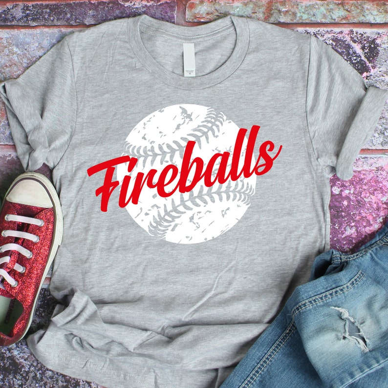 K&ouml;nnte beinhalten: Graues T-Shirt mit einem wei&szlig;en Baseball-Motiv und dem Text "Fireballs" in Rot.