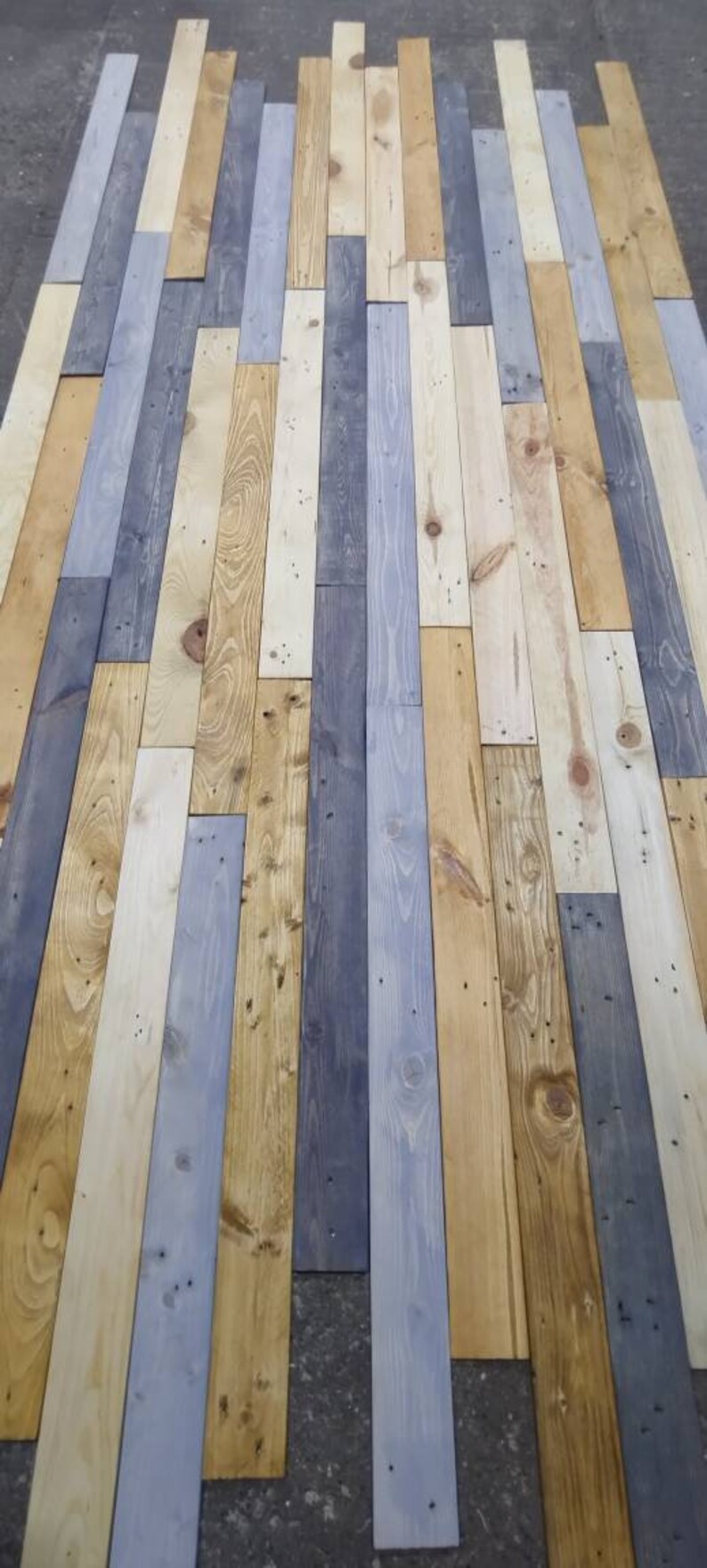 K&ouml;nnte beinhalten: Eine Wand aus wiederverwendeten Holzdielen in verschiedenen Graut&ouml;nen, Braun- und Beiget&ouml;nen. Die Dielen sind in einem versetzten Muster angeordnet, was einen rustikalen und einzigartigen Look erzeugt.