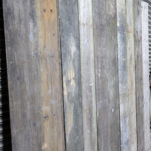 May include: A close-up of a wall made of reclaimed wood planks. The planks are various shades of brown, grey, and white, and have a weathered, rustic look.