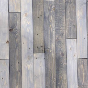 K&ouml;nnte beinhalten: Eine Wand aus wiederverwendeten Holzdielen in verschiedenen Graut&ouml;nen und Braunt&ouml;nen. Das Holz hat ein rustikales, verwittertes Aussehen mit sichtbaren Knoten und Maserungen.