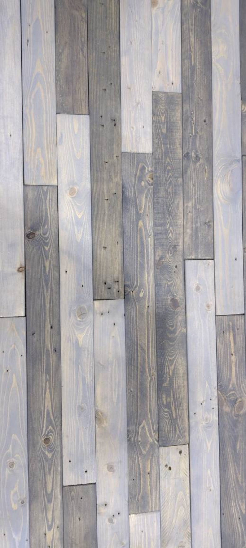 K&ouml;nnte beinhalten: Eine Wand aus wiederverwendeten Holzdielen in verschiedenen Graut&ouml;nen und Braunt&ouml;nen. Das Holz hat ein rustikales, verwittertes Aussehen mit sichtbaren Knoten und Maserungen.
