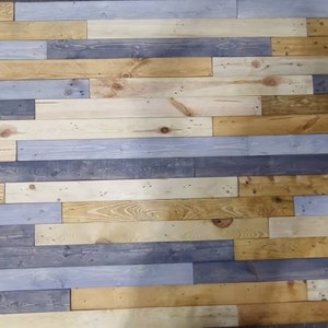 K&ouml;nnte beinhalten: Eine Wand aus wiederverwendeten Holzdielen in verschiedenen Blaut&ouml;nen, Braun- und Beiget&ouml;nen. Die Dielen sind horizontal angeordnet und erzeugen einen rustikalen und modernen Look.