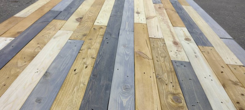 K&ouml;nnte beinhalten: Nahaufnahme eines Holzbodens aus wiederverwendeten Holzdielen in verschiedenen Graut&ouml;nen, Braun- und Beiget&ouml;nen.