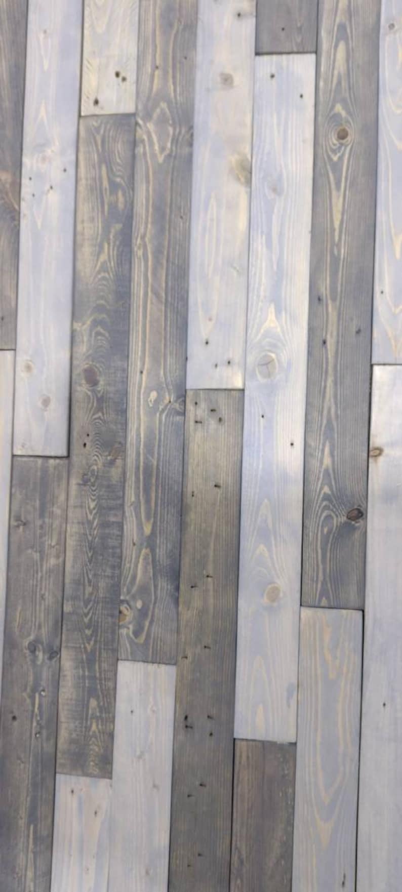 K&ouml;nnte beinhalten: Eine Wand aus wiederverwendeten Holzdielen, in Graut&ouml;nen und Wei&szlig; gestrichen. Das Holz hat ein rustikales, verwittertes Aussehen mit sichtbaren Knoten und Maserungen.