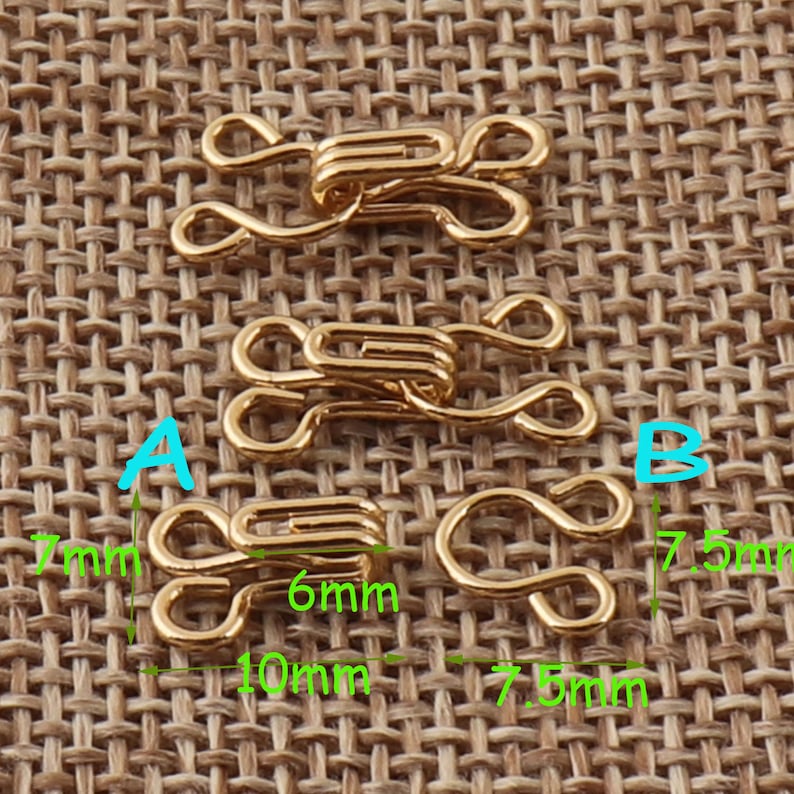 May include: Three gold-toned metal hook and eye closures. The largest closure measures 7.5 mm wide and 7.5 mm tall. The middle closure measures 6 mm wide and 10 mm tall. The smallest closure measures 7 mm wide and 7 mm tall.