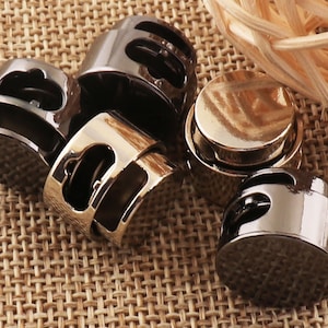 Può includere: Cinque chiusure a scatto in metallo in diverse finiture, tra cui nero, argento e oro. Le chiusure sono rotonde e hanno un piccolo anello laterale.
