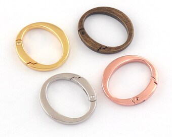 May include: Four oval-shaped metal key rings in different finishes: gold, bronze, rose gold, and silver.