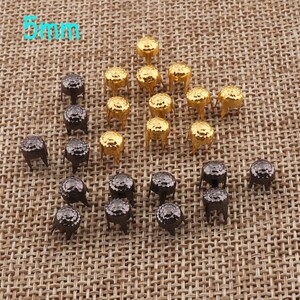 May include: A collection of 5mm metal studs in two colors: gold and black. The studs have a round head and three prongs on the bottom.