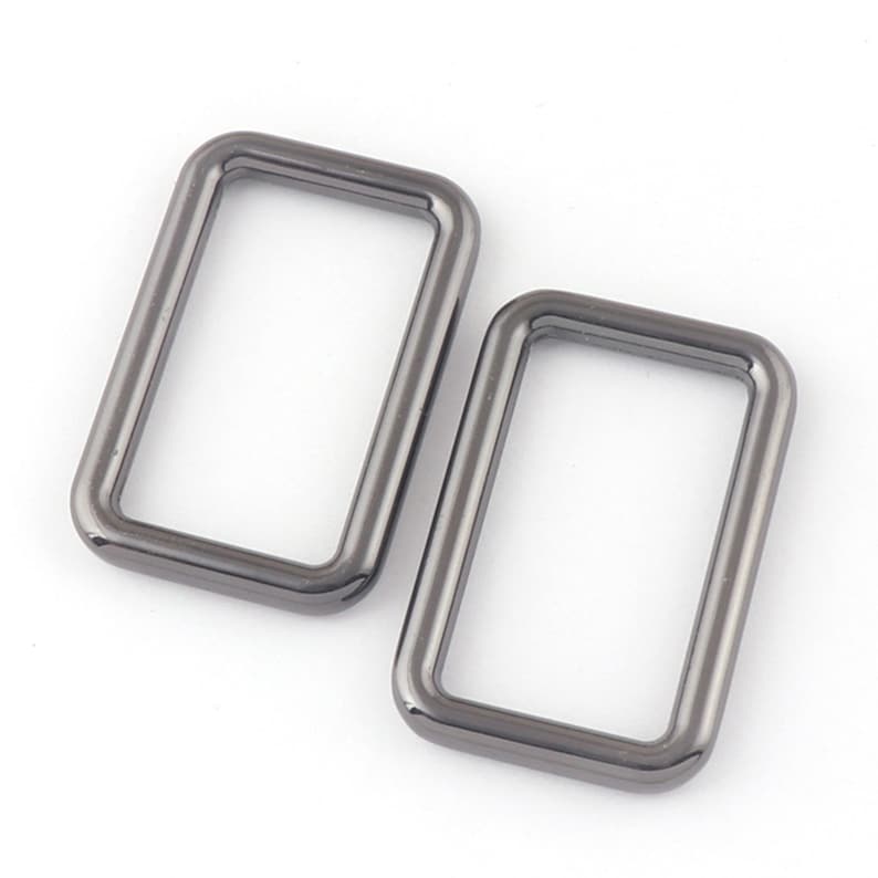 May include: Two silver-toned metal D-rings, each with a rectangular shape and a smooth, polished finish.