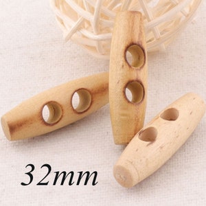 Puede incluir: Tres botones de madera con dos agujeros cada uno. Los botones son de color marrón claro y miden 32 mm de largo.