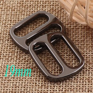 May include: Two black metal D-rings, one slightly larger than the other, with a shiny finish. The rings are 19mm in diameter.