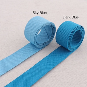 Puede incluir: Dos rollos de cinta azul, uno azul cielo y otro azul oscuro. La cinta es plana y tejida.