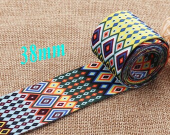 May include: A close-up of colorful patterned elastic trim with a geometric design. The trim is 38mm wide and is rolled up on a table.