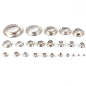 May include: Assortment of silver metal eyelets in various sizes. The eyelets are arranged in rows from largest to smallest.